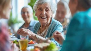 Elderly residents sitting together in a lounge area, chatting and participating in a group craft activity.